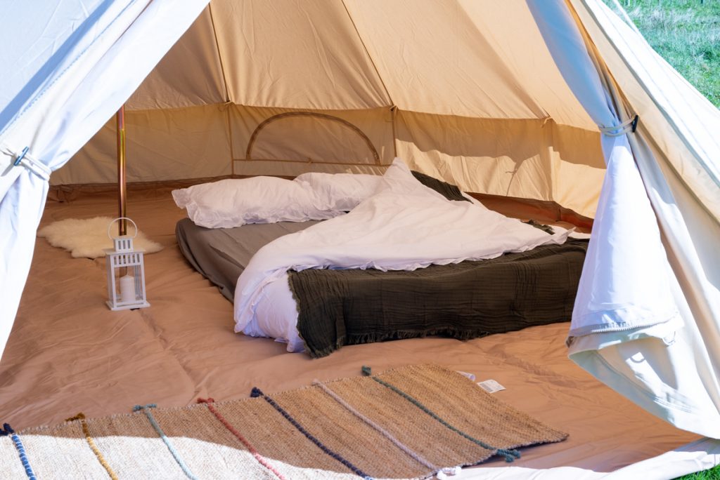Boutique glamping interior with double bed, premium linens, and fairy lights in a South Downs bell tent