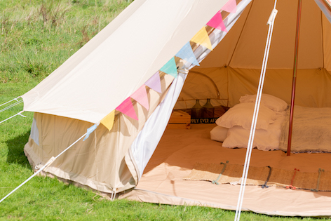 Boutique glamping interior with double bed, premium linens, and bunting for that reasonable luxury glamping price