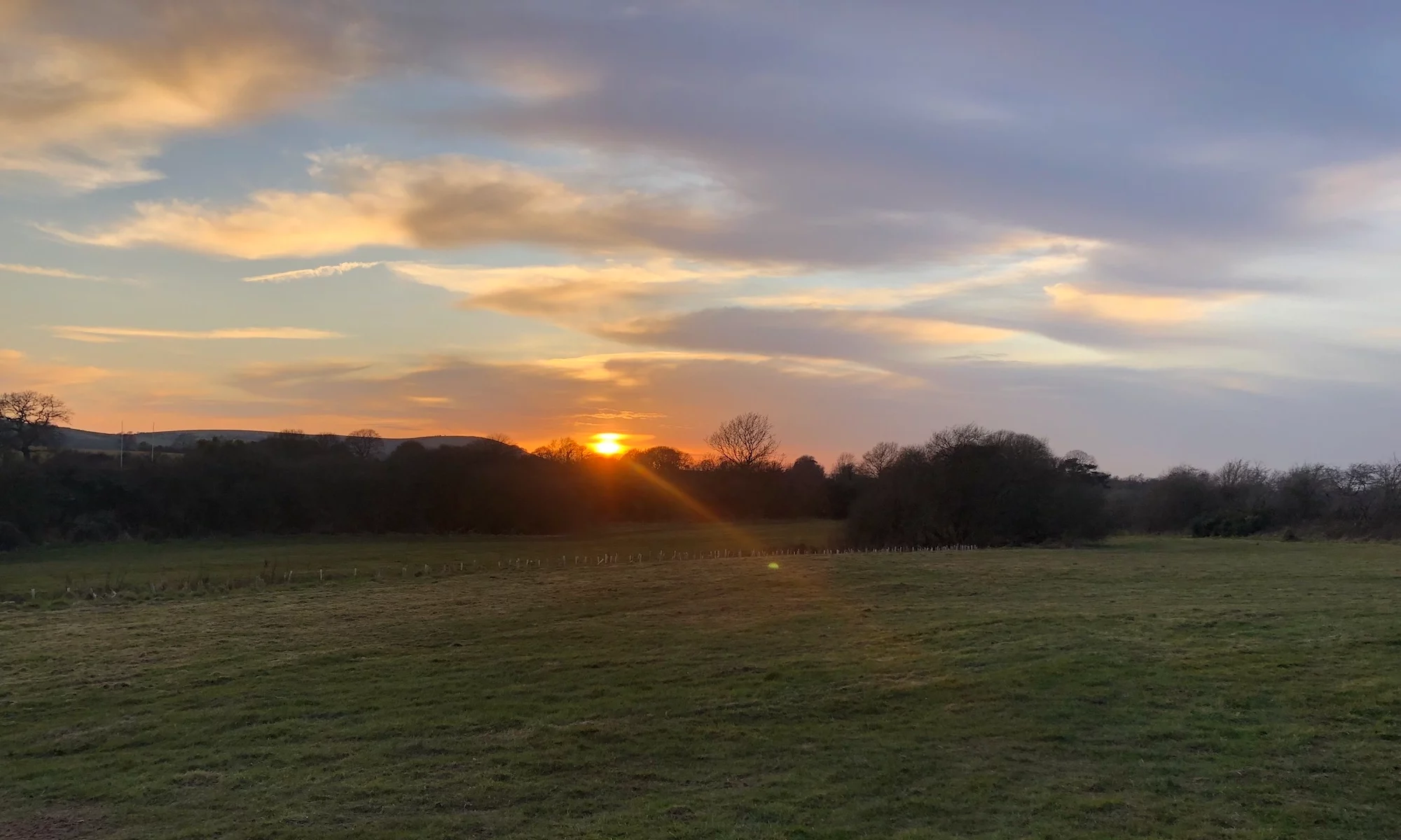 Golden sunset over the open camping fields at Ditchling Camping in the South Downs.